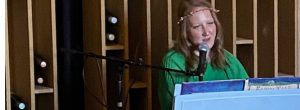 Emma Knights sitting at a piano in a green nymph costume